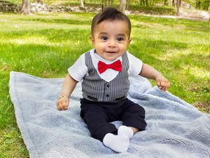 baby sits on blanket in grass in bowtie shirt